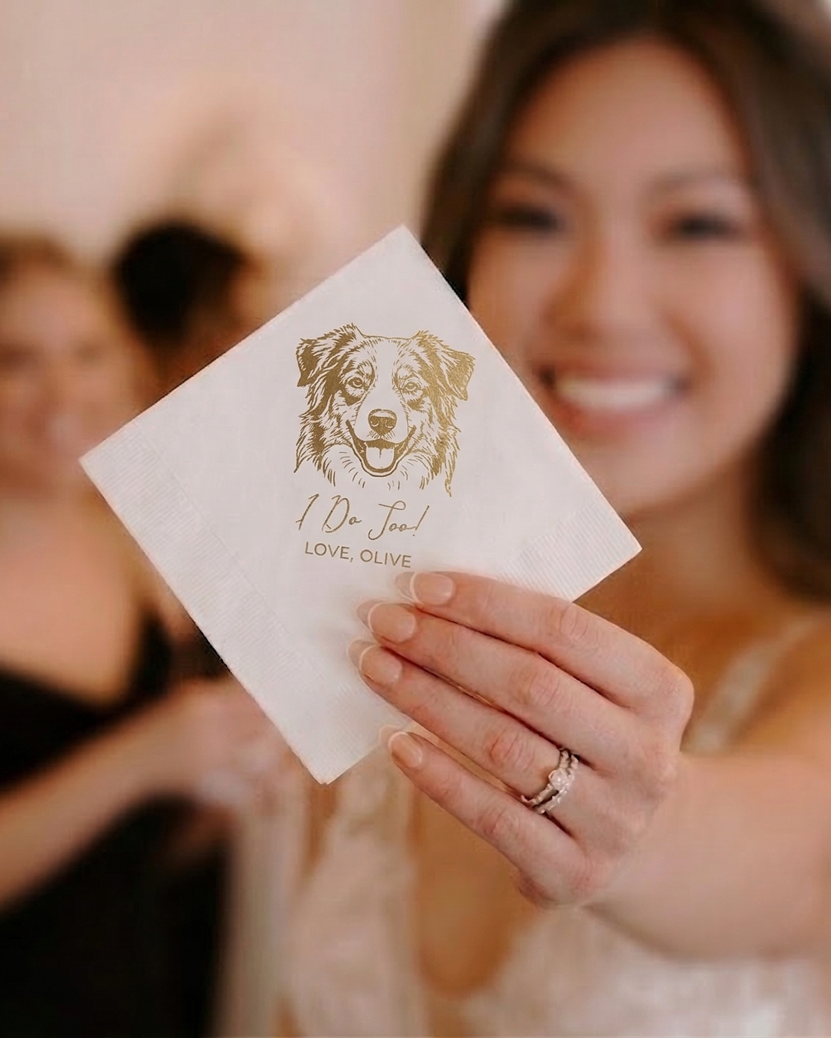 Woman holding a card with a dog illustration and text, blurred background
