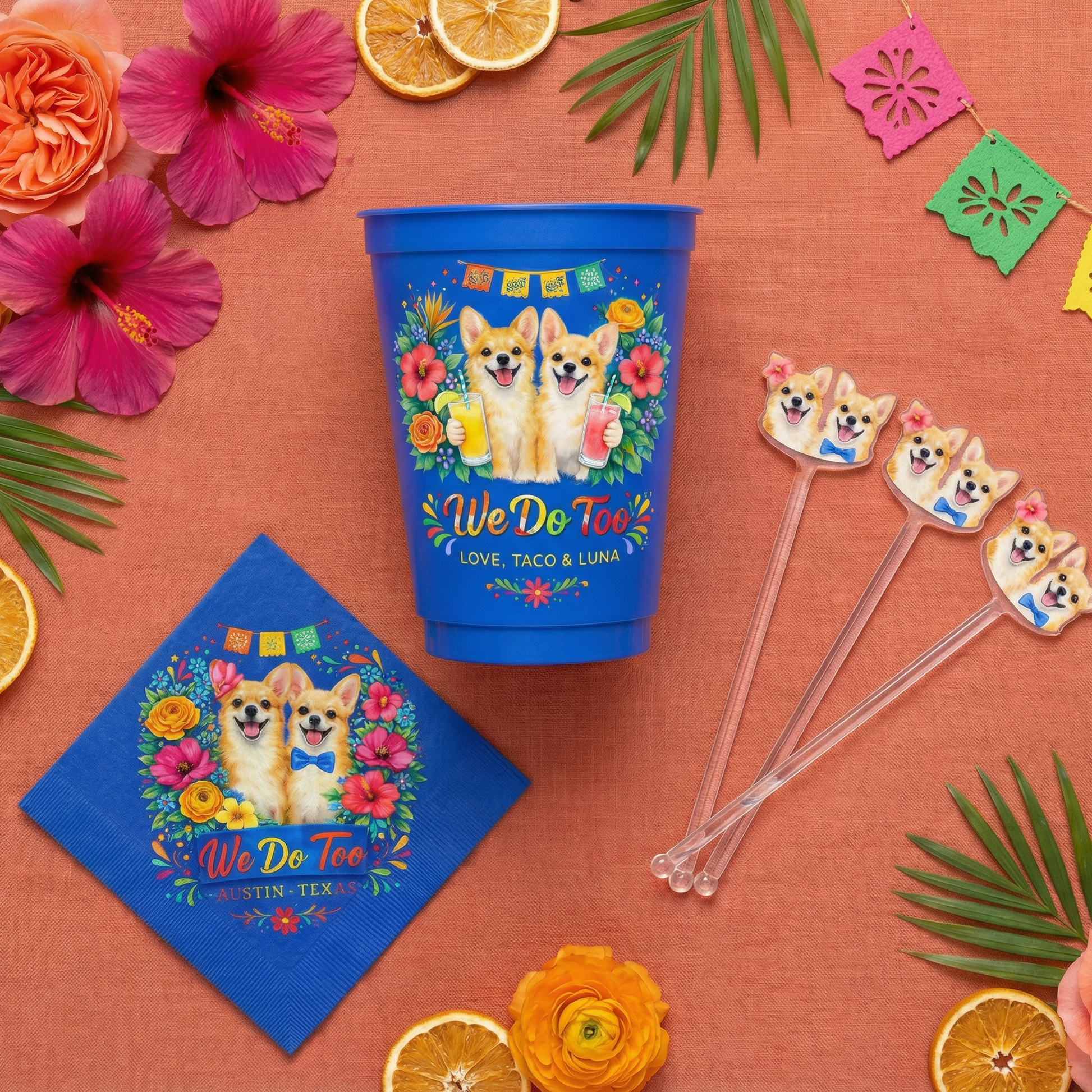 Colorful party set with a blue cup, napkin, and straws featuring corgi design on an orange background with flowers and leaves.