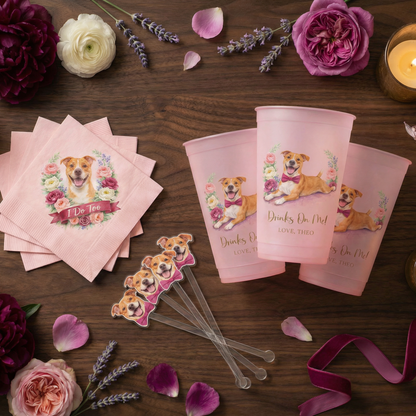 Pink party supplies with dog illustrations on a wooden table with flowers and candles.