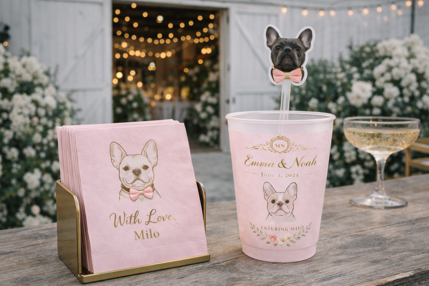 Pink cup with dog illustration and napkins on a wooden table outdoors.