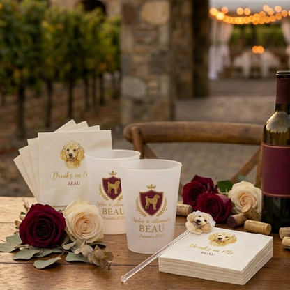 Wine-themed party supplies including cups, napkins, and a bottle on a wooden table with flowers.